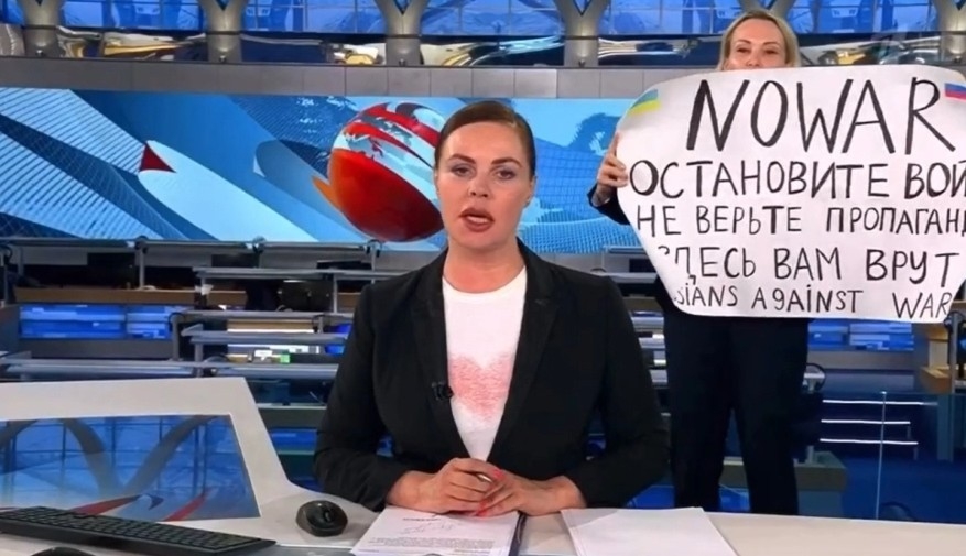 Marina Ovsyannikova, then a Channel One employee, interrupts Ekaterina Andreeva's broadcast with an anti-war sign, denouncing propaganda about the invasion of Ukraine. Image: Screenshot of Channel One broadcast