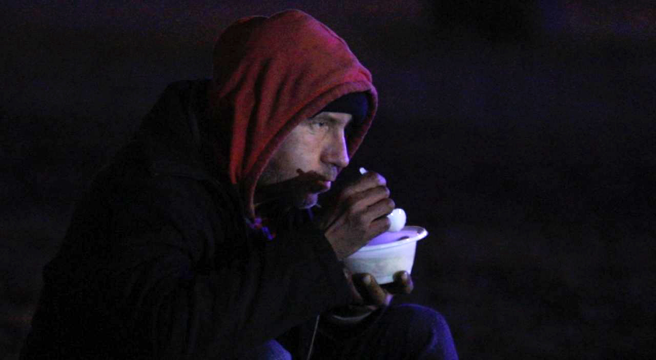 A homeless man eats soup at a warming station