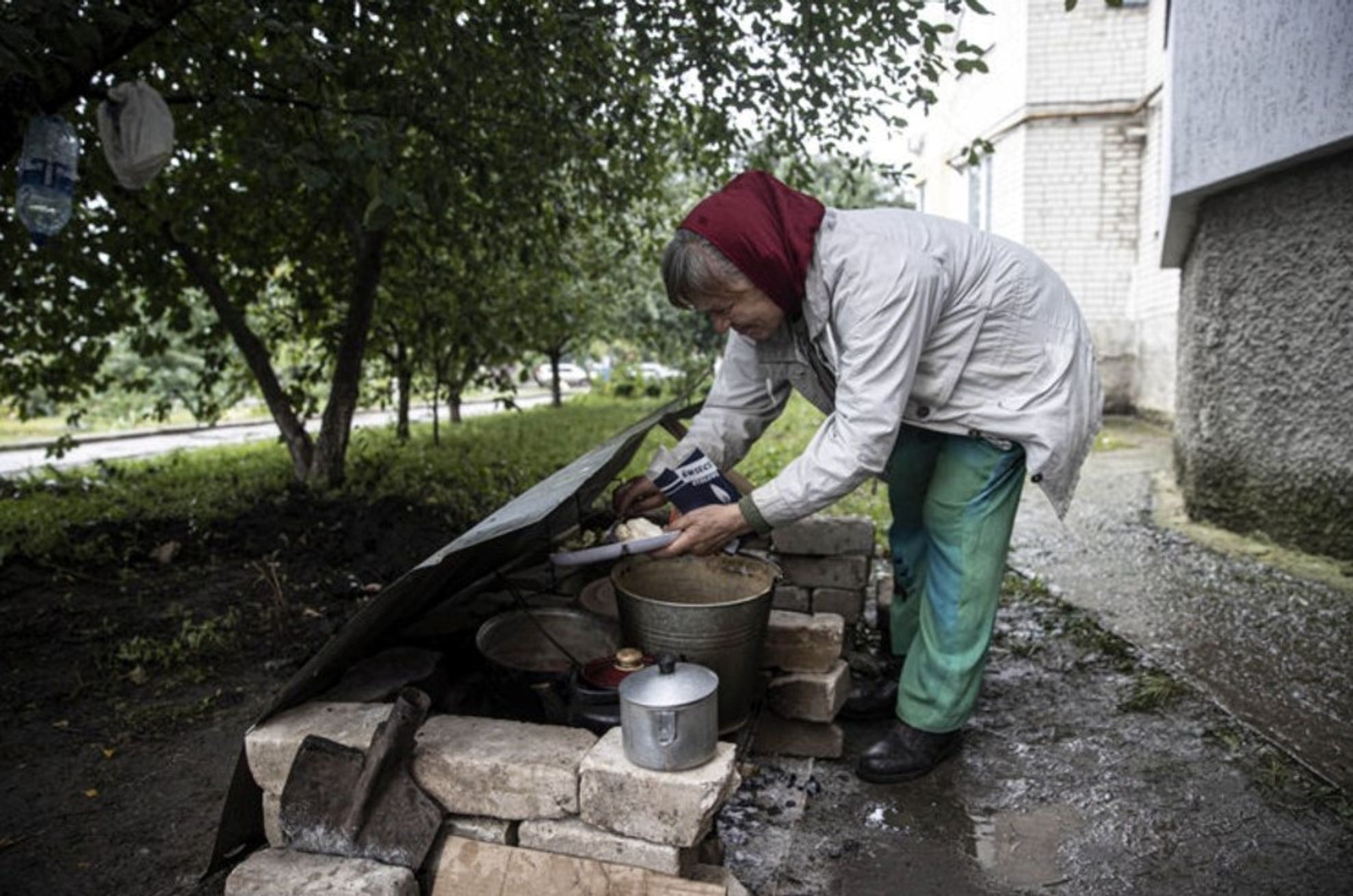 A woman in Kupiansk cooking food outside her apartment block