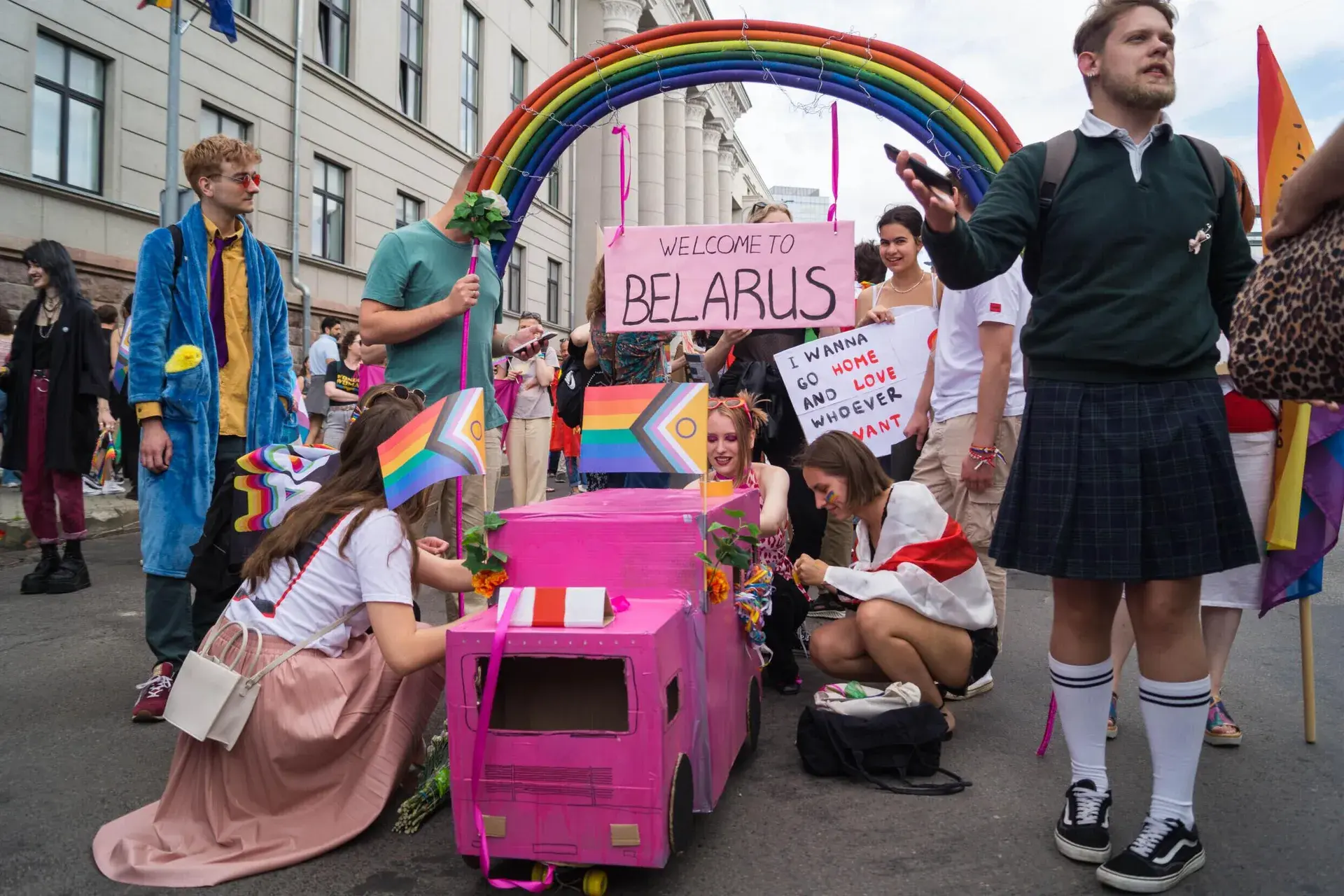 A group from Belarus displays a pink police van and a rainbow behind barbed wire at Vilnius Pride in July 2023. Photo: RFI
